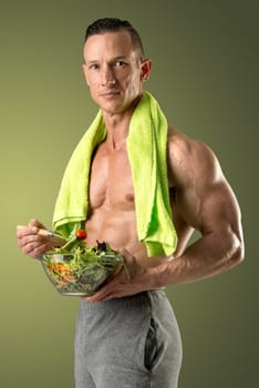 Powerful athletic man with great physique eating a healthy salad.