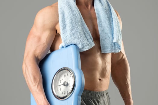Powerful athletic man with great physique holding a weight scale.
