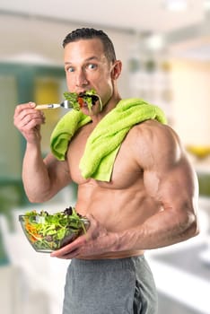 Powerful athletic man with great physique eating a healthy salad.