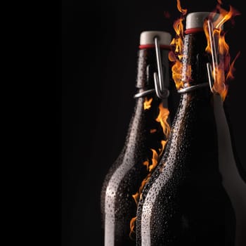 Cold beer bottle with cool drops and hot flames
