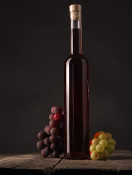 Bottle of red wine with grapes on a wooden table