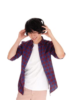A young handsome Korean teenager listen to music with his headset,.in a checkered shirt, isolated for white background..