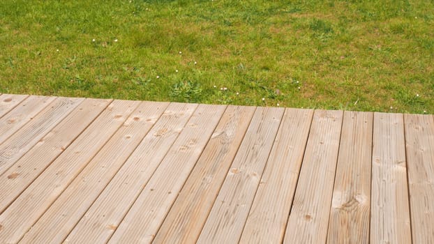 Wooden deck with grass in a garden, space for text or image, using as background