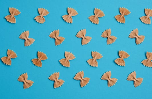 Pasta or noodles background, whole grain farfalle on blue, food concepts, view from above
