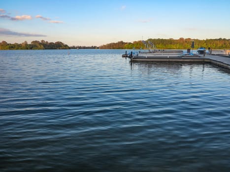 A lake with dock and boats, trees in distance