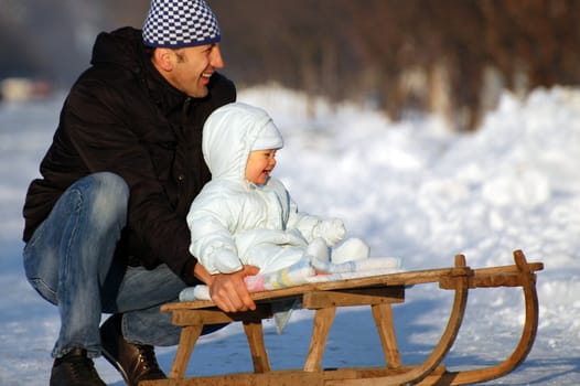 Happy father and his baby boy are sledding.