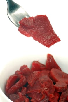 Thee beet as salad is on fork and in white plate on white background.