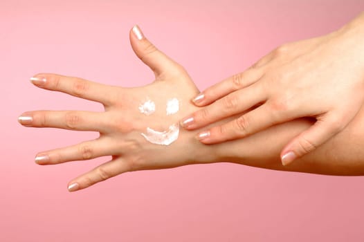 The hand is drawing smiley from hand cream on another hand.