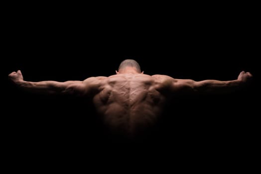 Muscular man's back in a dark background