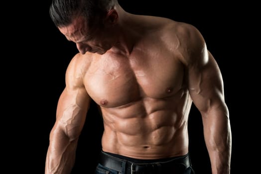 Power athletic man with great physique. Strong bodybuilder showing perfect body isolated in black.