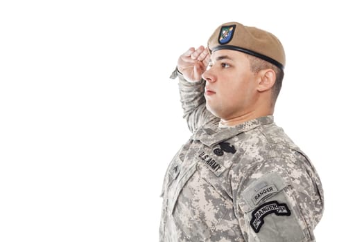 Army Ranger from Special Troops Battalion in universal Camouflage pattern Uniforms and Tan beret with Ranger Regiment crest is standing to attention and saluting proudly with honor and respect. Service to his country concept. National holidays, Veterans Day, Memorial Day. National Anthem is played