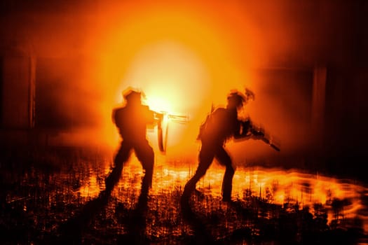 Dark silhouettes of pair of soldiers moving in battle operation. Back light