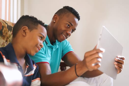 Happy black family at home. African american father and child playing game with tablet. Dad and son having fun with laptop computer