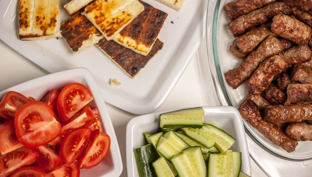 table with plates grilled cevapcici cheese tomatoes cucumbers balkan cuisine