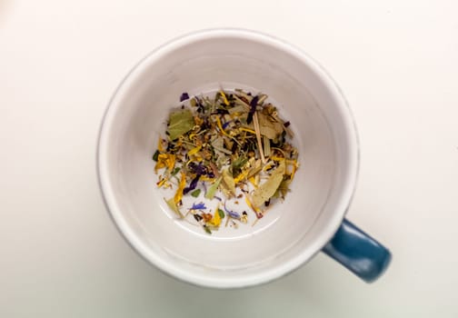 cup with herbs without water on white background