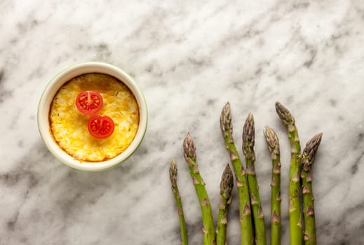 fresh green asparagus and casserole on white marble background