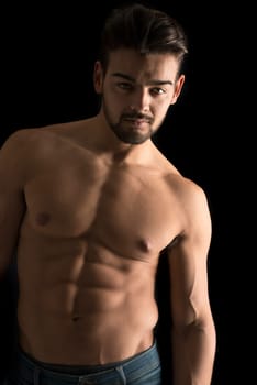Handsome young man, shirtless, with great body posing over a black background