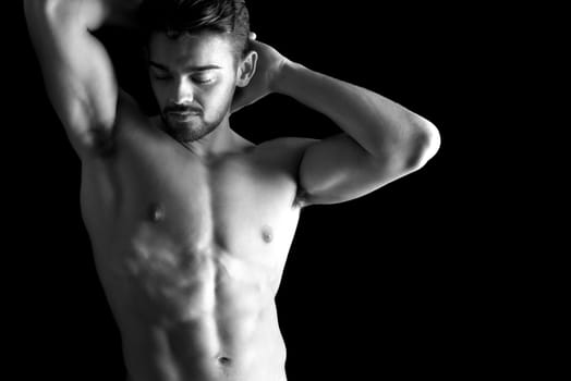 Handsome young man, shirtless, with great body posing over a black background