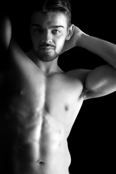 Handsome young man, shirtless, with great body posing over a black background