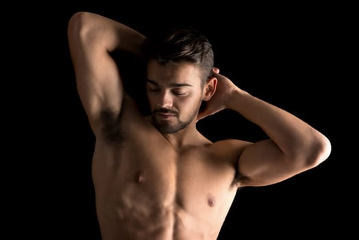 Handsome young man, shirtless, with great body posing over a black background