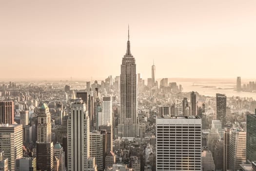 New York City. Manhattan downtown skyline with sun illuminated Empire State Building and skyscrapers at sunset.
