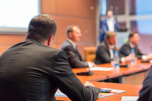Manager giving a talk on corporate business event. Company managemant taking decisions at board room. Business and Entrepreneurship event. Focus on unrecognizable businessman in front.