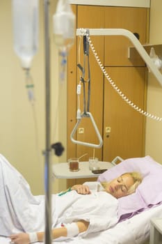 Bedridden female patient lying in hospital bed, recovering after surgery.