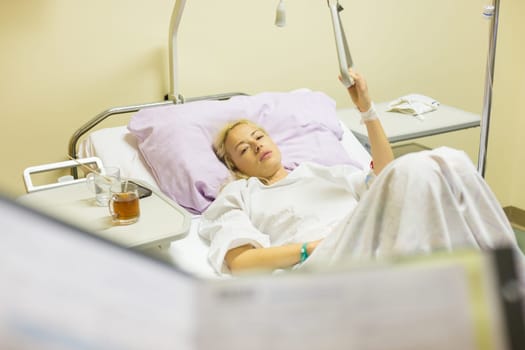 Bedridden female patient lying in hospital bed, recovering after surgery.