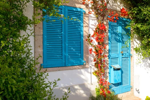 Typical Mediterranean house with white walls and blue fixtures. Boungaville flowers frame the windows.