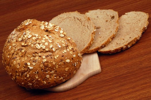 Bread on cutting board is on wooden table.