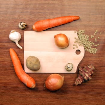 Cutting board with different vegetables on wooden background.