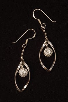The silver earrings are on black background.