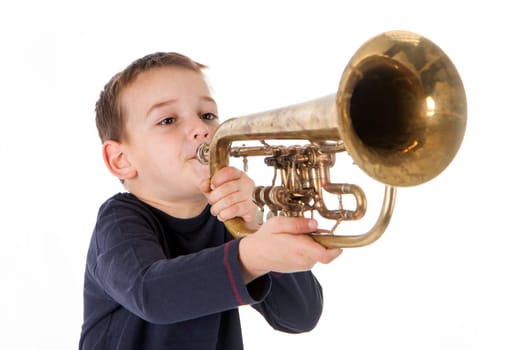 young boy blowing into a trumpet against white background
