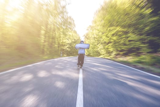 Panning shot of boy walking through a road in the middle of a forest
