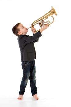 young boy blowing into a trumpet against white background