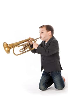 young boy blowing into a trumpet against white background