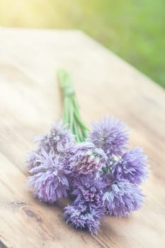 Flower chives tied in a snop on a natural wooden cutting board