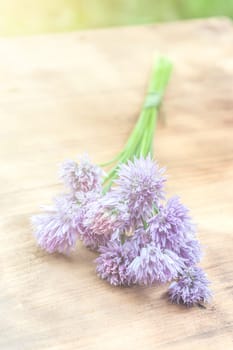 Flower chives tied in a snop on a natural wooden cutting board