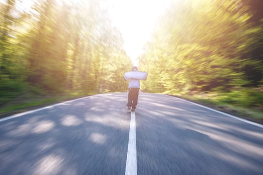 Panning shot of boy walking through a road in the middle of a forest