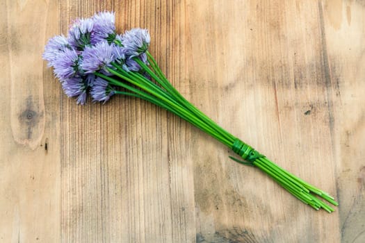 Flower chives tied in a snop on a natural wooden cutting board