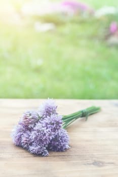 Flower chives tied in a snop on a natural wooden cutting board