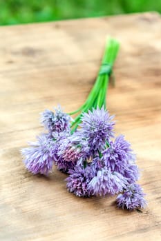 Flower chives tied in a snop on a natural wooden cutting board