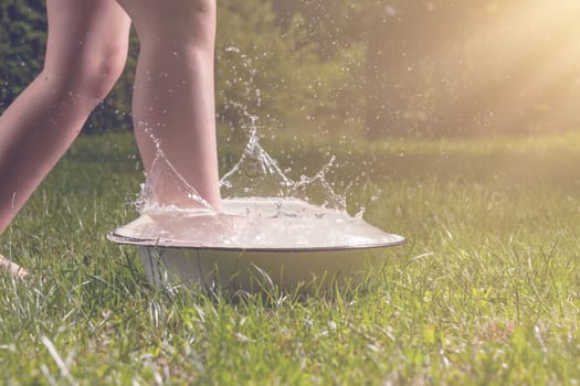 Little boy and splash of water in the summer garden
