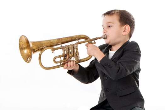young boy blowing into a trumpet against white background