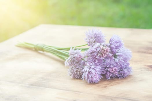 Flower chives tied in a snop on a natural wooden cutting board