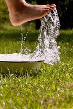 Little boy and splash of water in the summer garden