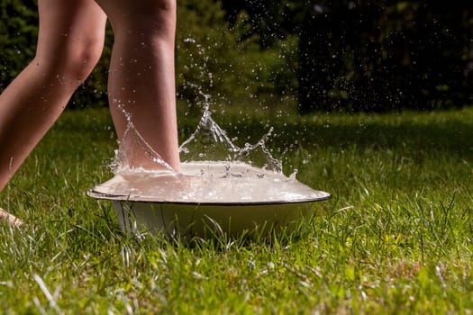 Little boy and splash of water in the summer garden
