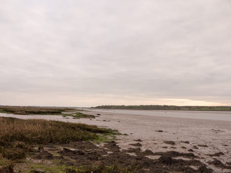 Low tide summer sky nightfall grey clouds mood and reds with river running through in wivenhoe essex uk england