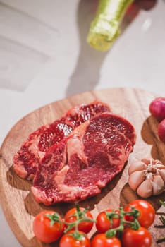 Raw beef on a cutting board with spices and ingredients for cooking.