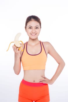 Smiling sporty asian  woman holding banana over white background and looking at camera